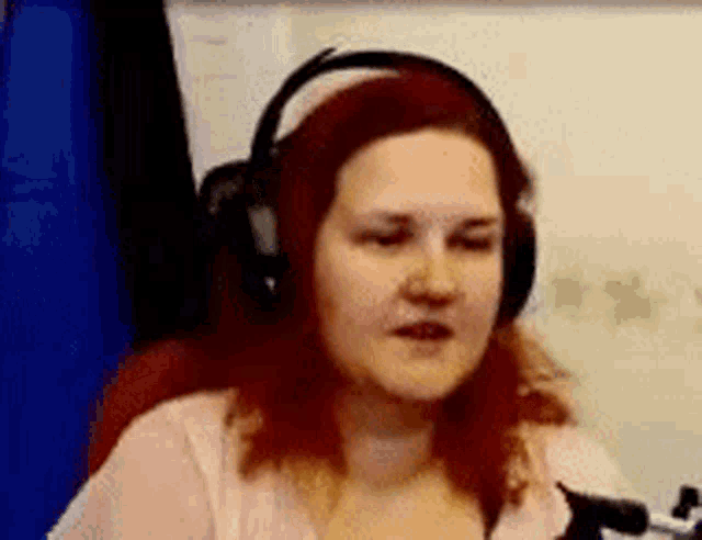 a woman with red hair wearing headphones is sitting in front of a microphone .