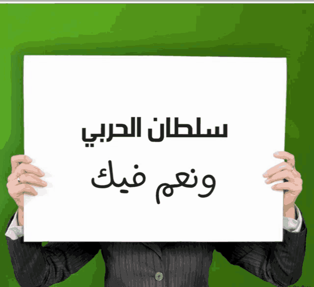 a man in a suit holds up a sign that says ' سلطان الحربي ' on it