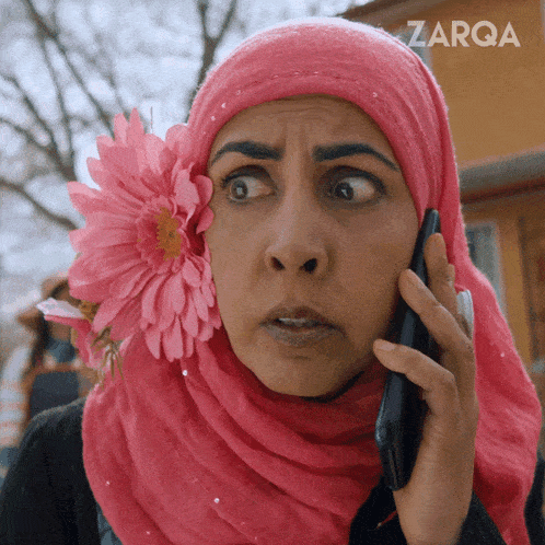 a woman with a flower in her hair is talking on a cell phone and the word zarqa is on the bottom