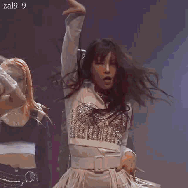 a group of women are dancing on a stage and one of them is wearing a white dress .