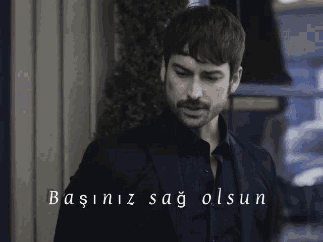 a man in a suit stands in front of a sign that says başiniz sağ olsun