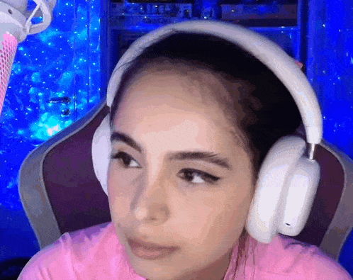 a woman wearing headphones and a pink shirt is sitting in front of a microphone .