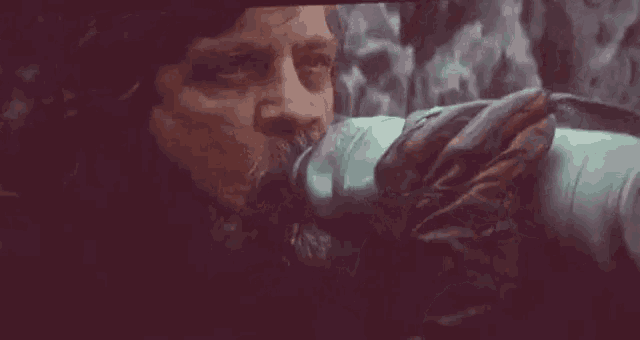 a man with a beard is drinking water from a bottle .