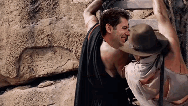 a man in a cowboy hat is holding another man up