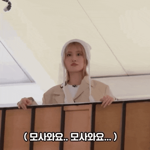 a woman wearing a white hat is looking over a railing with a caption in korean
