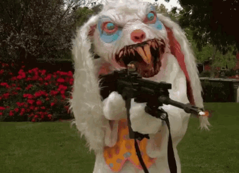a stuffed bunny is holding a gun in a garden