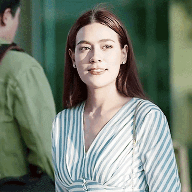 a woman wearing a blue and white striped shirt is looking at the camera