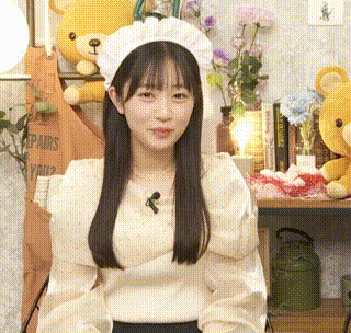 a woman wearing a white hat and a white sweater is sitting in front of a table with stuffed animals .