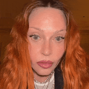 a close up of a woman 's face with red hair and a white shirt