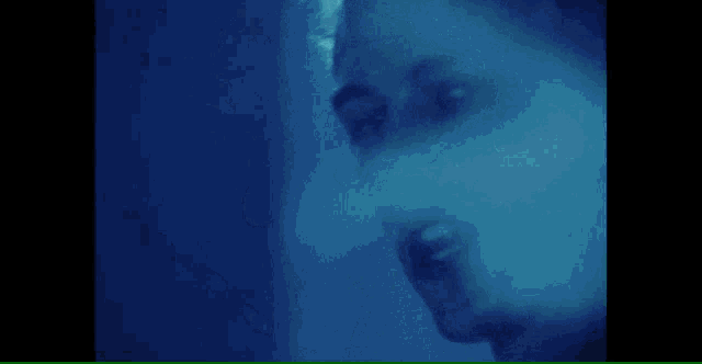 a close up of a man 's face in a blue light .