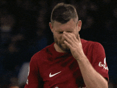 a soccer player wearing a red shirt that says standard chartered
