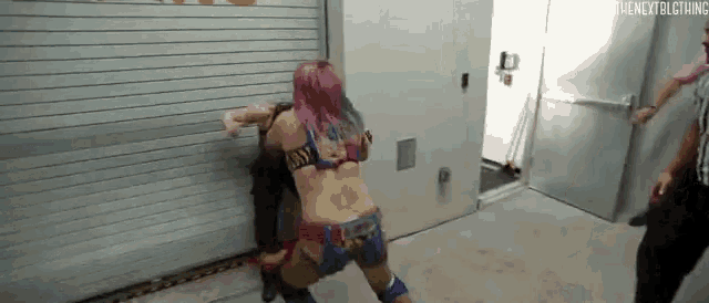 a woman with pink hair is fighting another woman in a wrestling match .