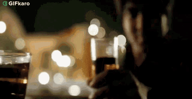 a man is sitting at a table holding a glass of beer and a cell phone .