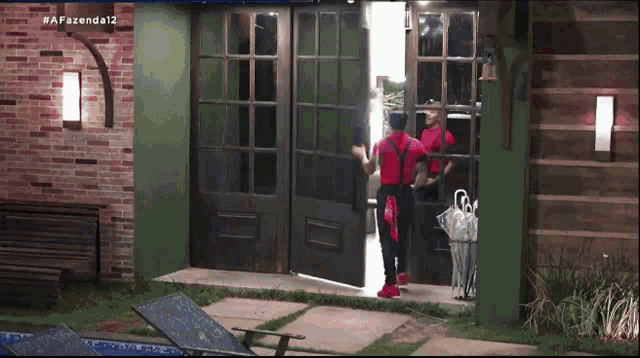 a man in red overalls is standing in front of a door that says afazenda12