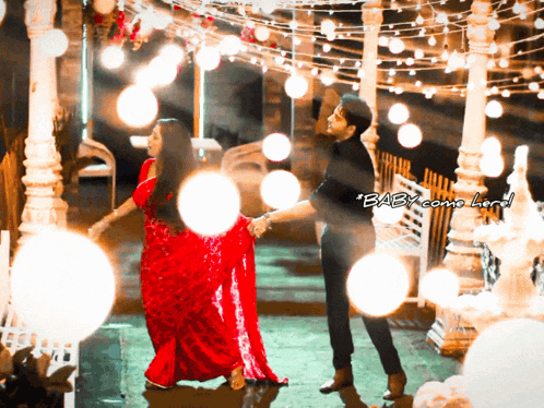 a woman in a red dress is dancing with a man in black pants