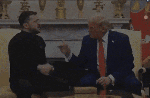 a man sitting next to a man in a suit and tie talking