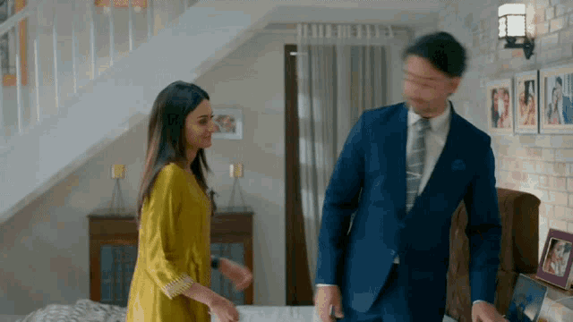a man in a suit and tie is walking with a woman in a yellow dress
