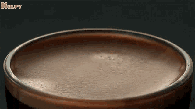 a container of chocolate ice cream has a hole in the middle and the word kulfy is on the bottom