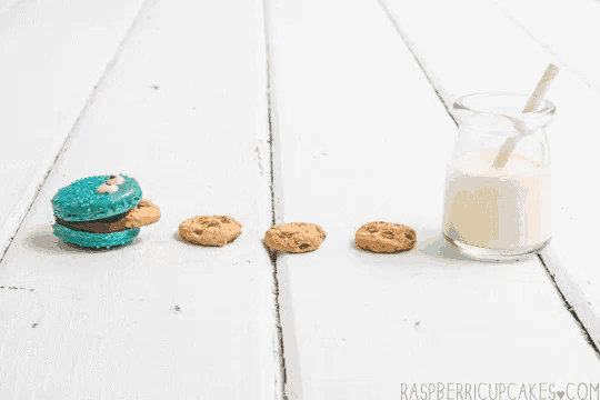 a cookie and a glass of milk on a table with the website raspberrycupcakes.com written on the bottom