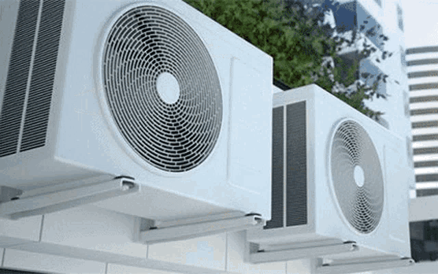 two white air conditioners are mounted on a building .