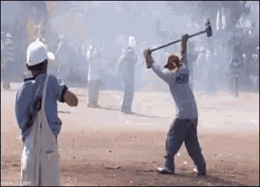 a man is holding a hammer in his hand while another man watches .