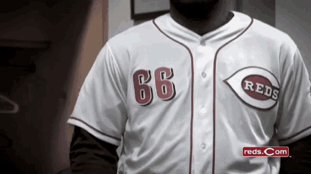 a man wearing a reds jersey with the number 66 on the front