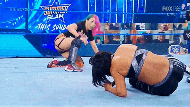 two women are wrestling in a ring and one is laying on the ground .