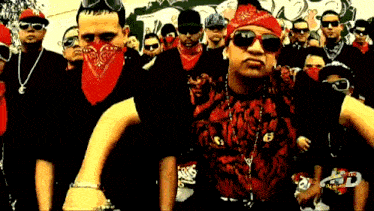 a group of men wearing red bandanas and sunglasses are standing in a crowd .