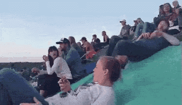 a group of people are sitting on a green hill .