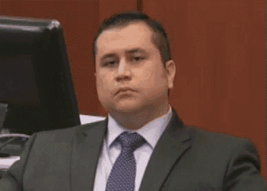 a man in a suit and tie is sitting in front of a computer screen .