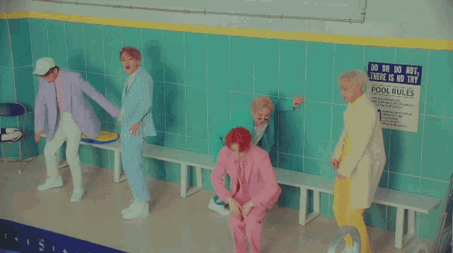 a group of young men are dancing in front of a sign that says pool