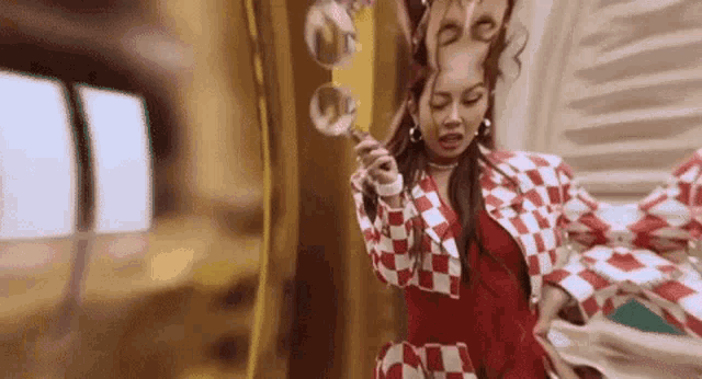 a woman in a red and white checkered jacket is blowing soap bubbles in a room .