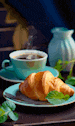 a croissant and a cup of coffee are on a table .