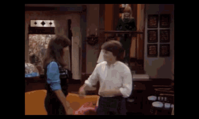 two people hugging each other in a living room with a lamp in the background