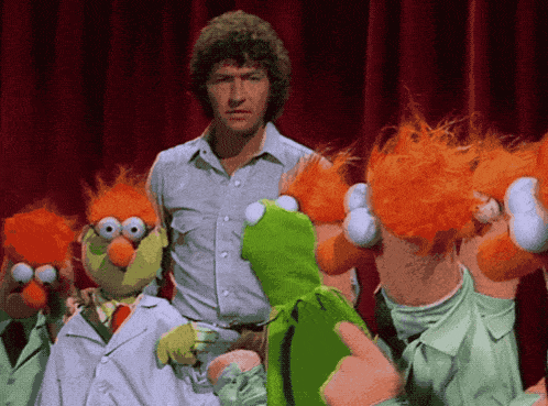 a man stands next to a group of muppets