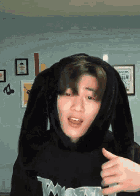 a young man wearing bunny ears and a black hoodie giving a thumbs up