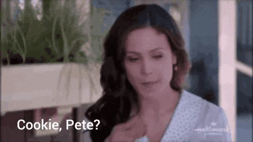 a woman is sitting at a table with a cookie in her hand and the words `` cookie , pete '' written on the screen .