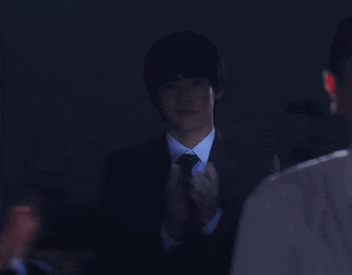 a man in a suit and tie is talking to another man