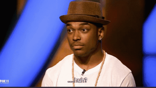 a man wearing a hat and a necklace says " huh "