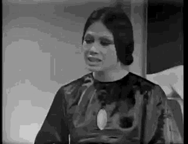 a black and white photo of a woman in a black dress talking to a man .