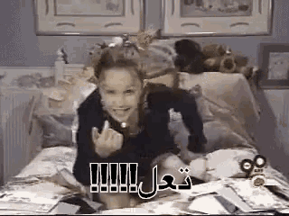 a young girl is sitting on a bed with a bunch of stuffed animals in the background .