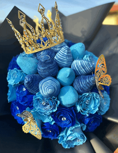 a bouquet of blue roses and strawberries with a crown on top