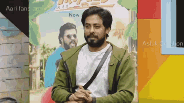 a man with a beard is standing in front of a poster that says aari fans army