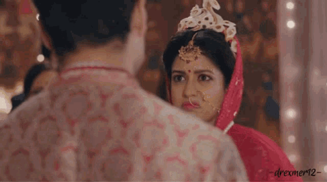a man and a woman are standing next to each other in a room . the woman is wearing a red dress .