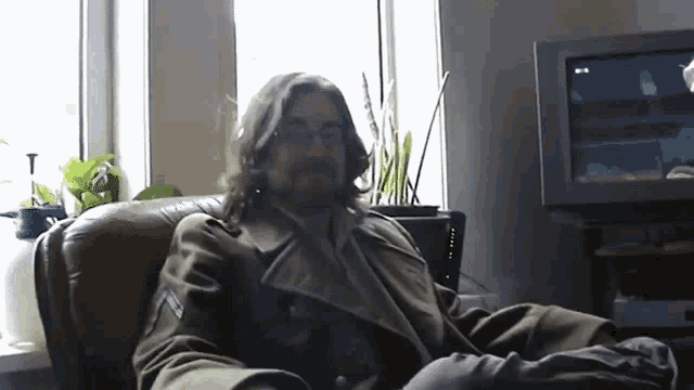 a man sits in a chair in front of a television that says ' tnt ' on it