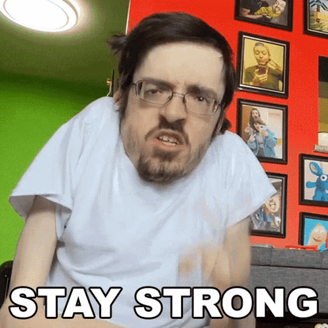 a man wearing glasses and a white shirt with the words stay strong written on it