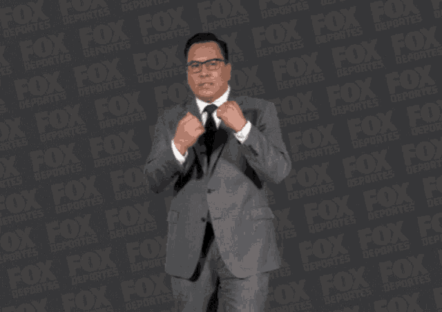 a man in a suit and tie is standing in front of a fox logo