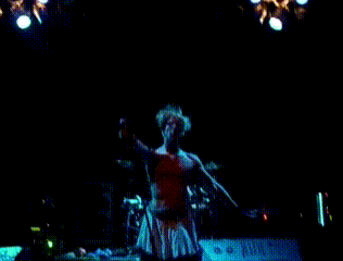 a man stands on a stage in front of a microphone with a sign in the background that says ' hawaii '