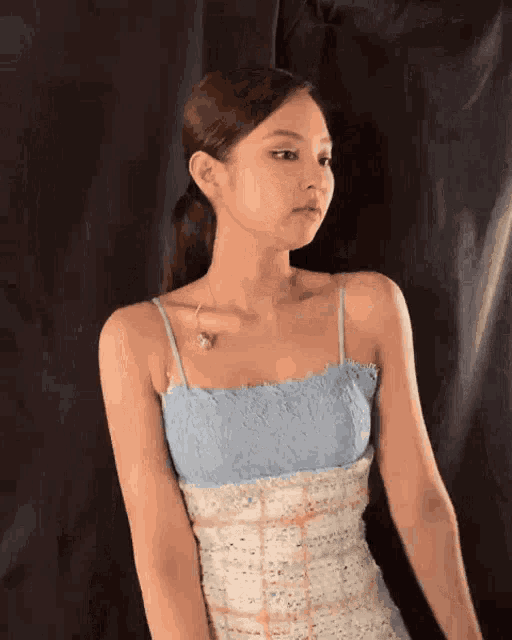 a woman in a blue and white dress is standing in front of a black curtain .