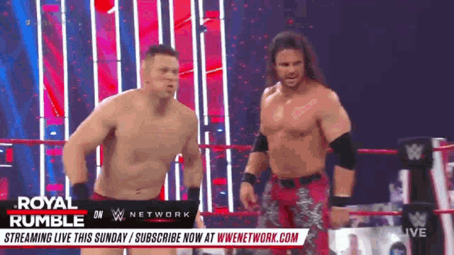 two men are standing in a wrestling ring on a wrestling show .